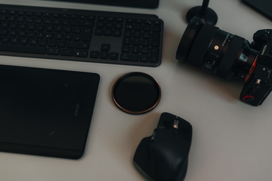 a camera, mouse, keyboard and mouse pad on a desk