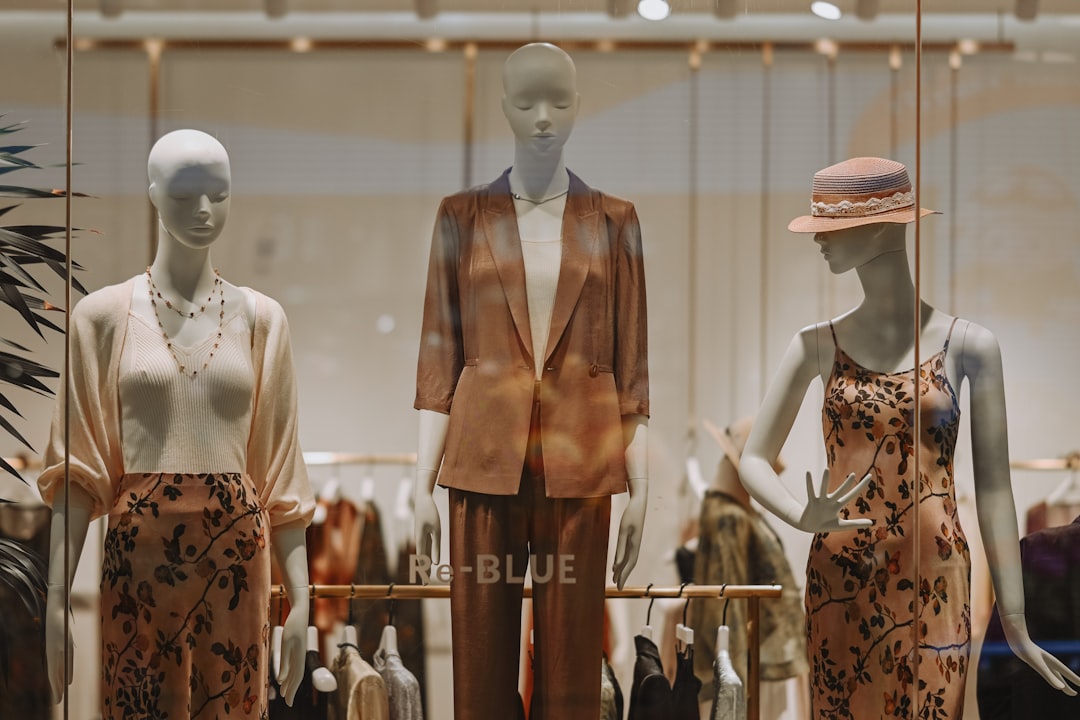 Three mannequins display fashionable clothing in a store window.